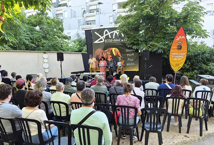 Des adhérents lisent leurs textes sur scène, devant le public assis dans le jardin