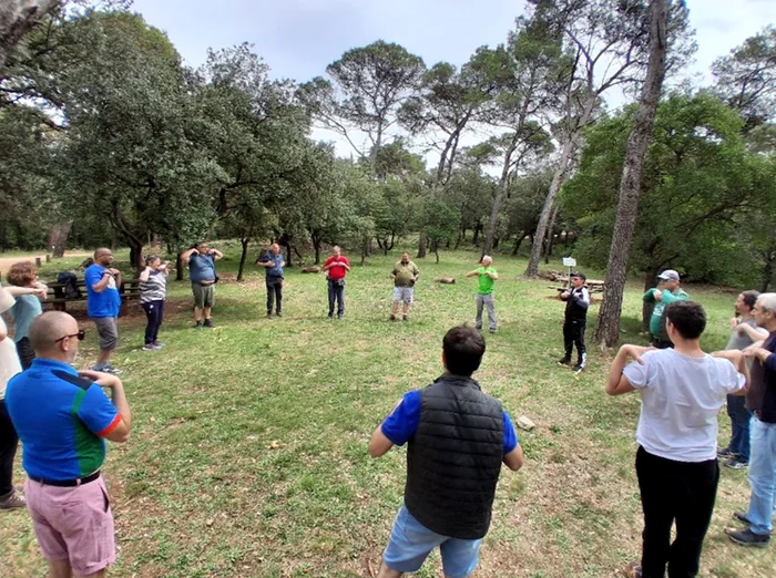 Les randonneurs en cercle sous les pins, bras levés pour un stretching collectif