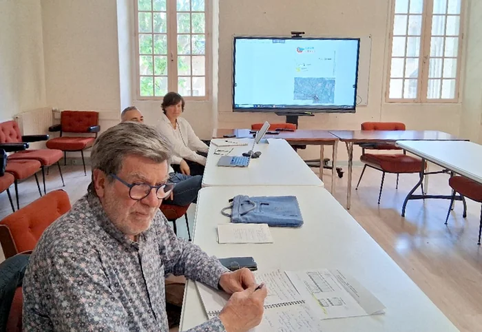 Réunion de travail en mairie de Pézenas : un participant prend des notes devant l’écran qui affiche le plan de la zone